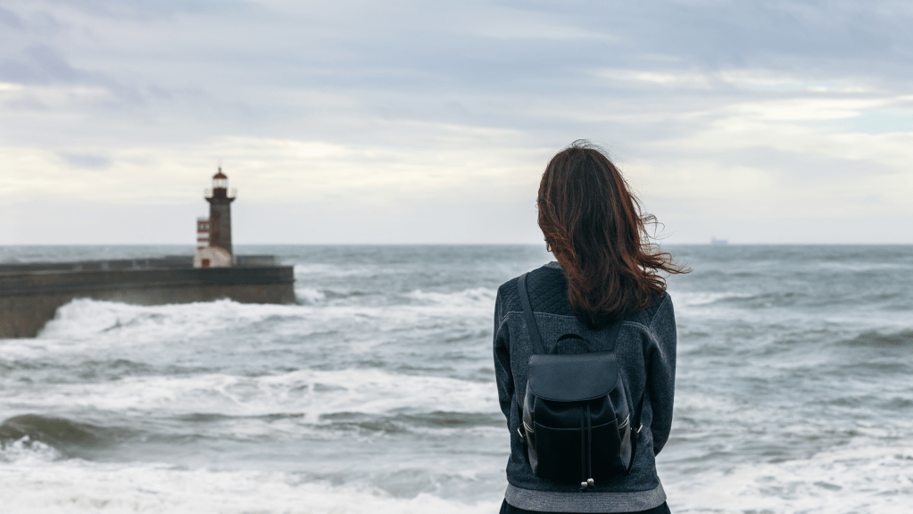 Girl looking over ocean at lighthouse 